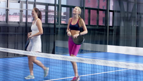 group of friends enjoying padel tennis match, celebrating on indoor court with smiles