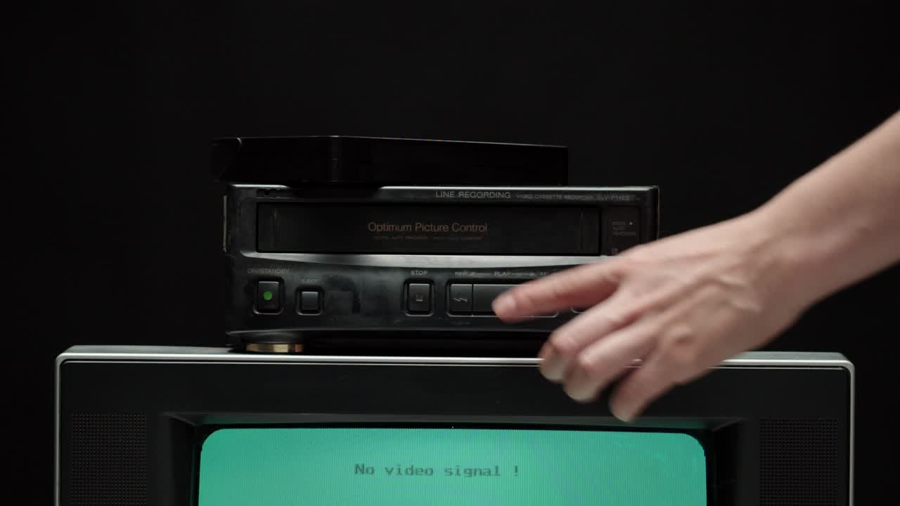 poniendo cassette de video en la grabadora. vieja televisión retro con pantalla azul sobre fondo negro. televisión anticuada, concepto de ajuste de televisión, ondas e interferencias, búsqueda de canal
