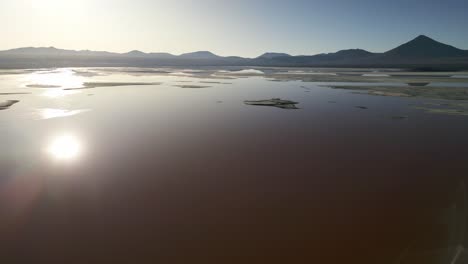 laguna colorada, aerial drone above red lake lagoon, sun reflects water, bolivia travel and tourism, unpolluted latin america