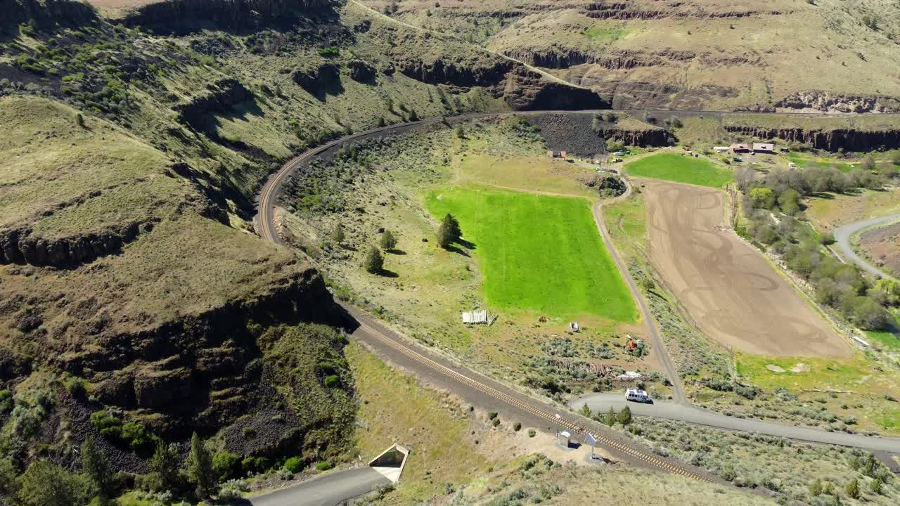 US, Oregon, Madras, Trout Creek, 2025-04-19 - Drone view one vehicle tunnel under a railroad train track and its arcing path along the canyon wall in central Oregon