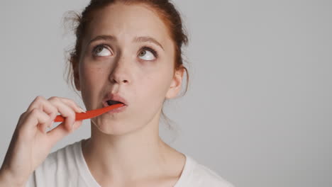 redheaded girl in front of camera on gray background.