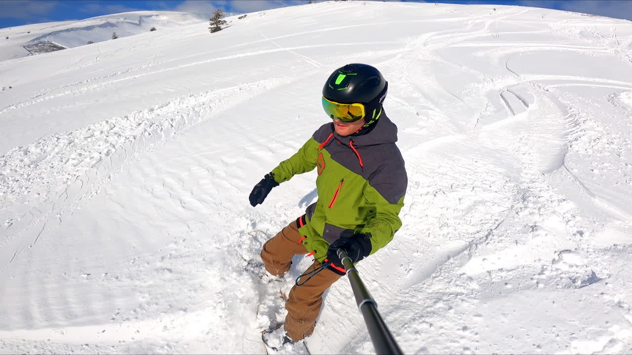 Enjoying a ride down the mountain slope on a beautiful sunny day. First person view of a snowboarder going down the hill.