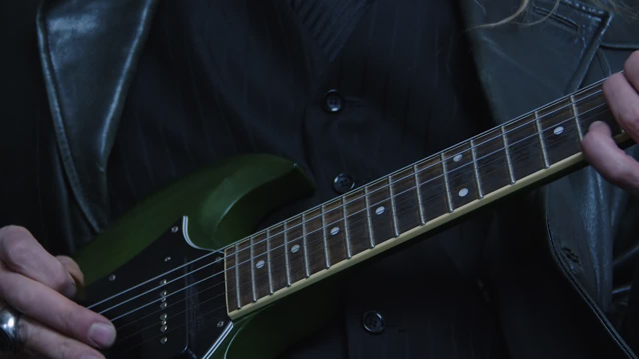 Close-up detail of musician playing green SG electric guitar, dark