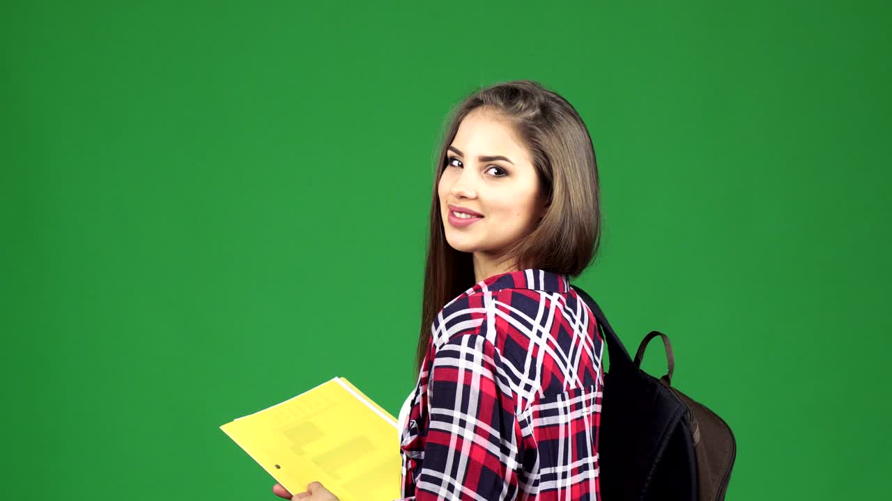 Splendida studentessa allegra che sorride sopra la spalla
