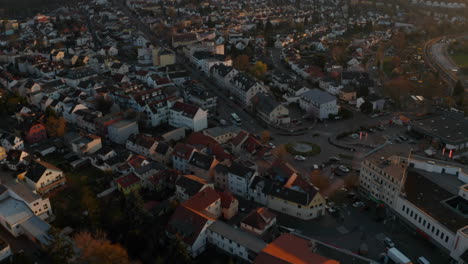 Drone-Volando-Sobre-Una-Pequeña-Ciudad-Balneario-A-La-Luz-Del-Atardecer.-Incline-Hacia-Arriba-Revelando-El-Horizonte-De-La-Ciudad-De-Frankfurt-Am-Main.-Mal-Vilbel,-Alemania.