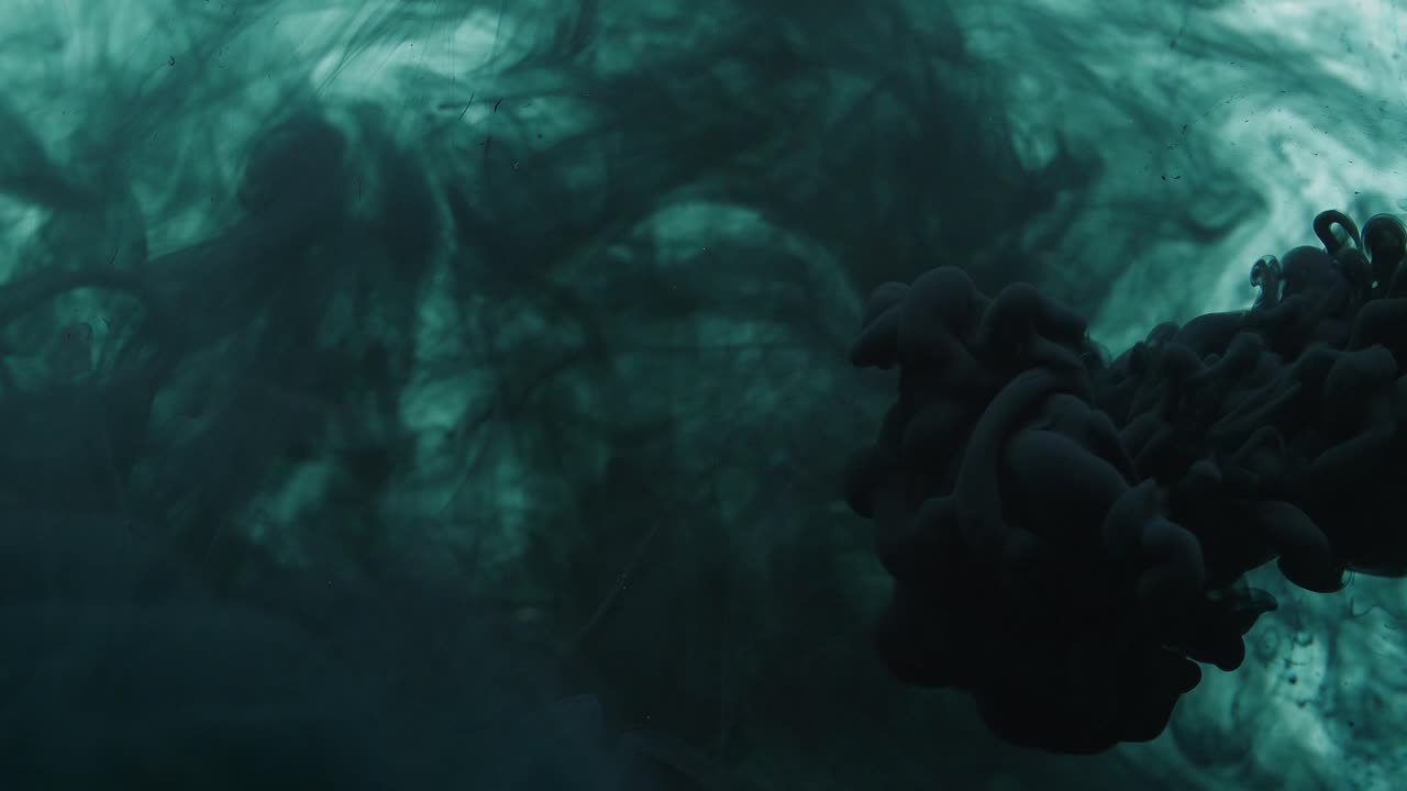 Black Ink Sprayed Into Grey Ink In Water On A White Background