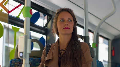 una mujer bonita se sube al autobús y se sienta en un asiento libre y mira a su alrededor