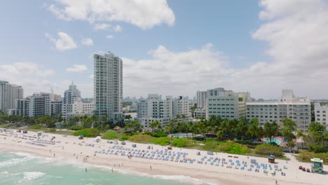 Forwards-fly-above-beach-on-sea-coast-in-tropical-vacation-resort.-Revealing-skyline-with-downtown-skyscrapers.-Miami,-USA