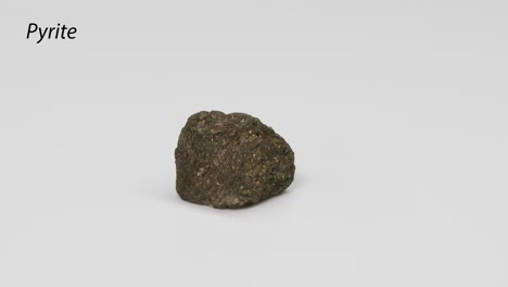 una roca de pirita girando sobre un fondo blanco