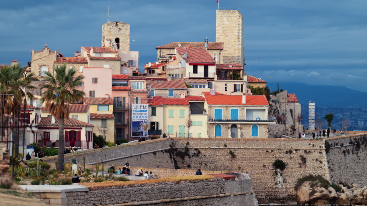 Antibes, France - February 20, 2025: Distant view of people walking on the coast near the Picasso Museum Castle