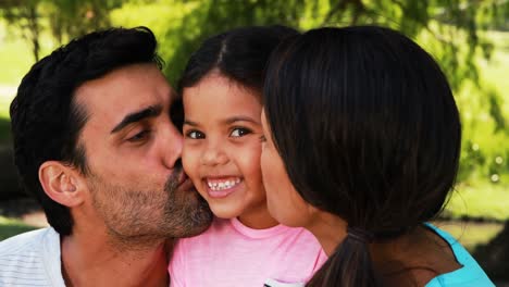 Girl-being-kissed-by-his-parents-in-park