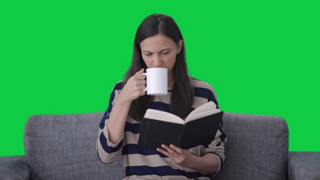 Confused-Indian-girl-reading-book-and-drinking-coffee-Green-screen