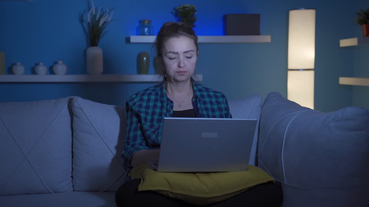 Unhappy woman using laptop laptop at night. It's not in a good mood.