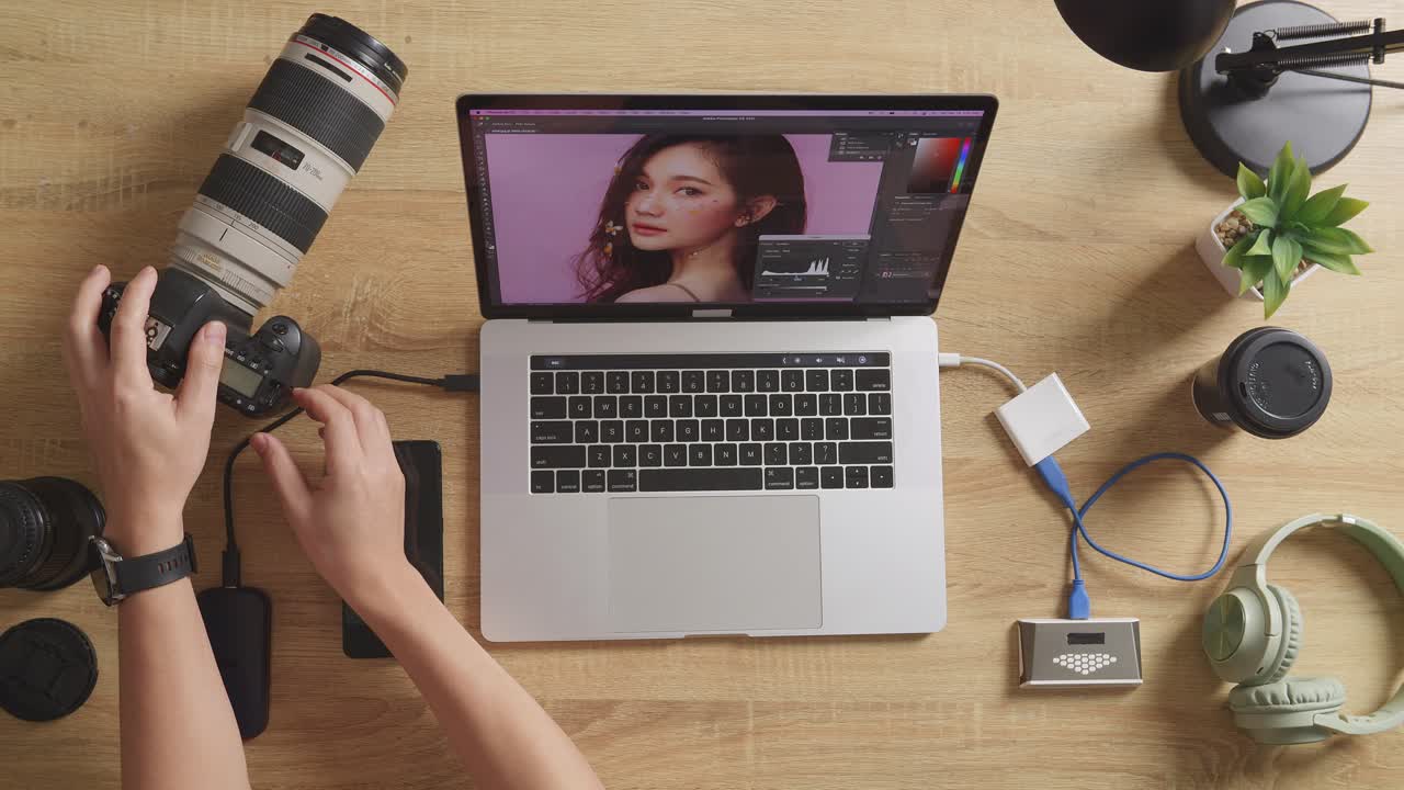 vista superior de cerca de las manos del editor masculino poniendo la tarjeta de memoria en una computadora portátil para elegir las fotos en el espacio de trabajo en casa