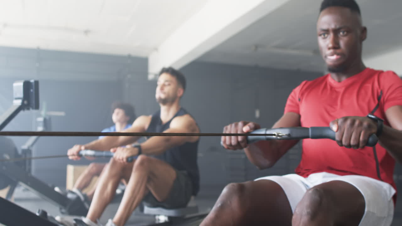 Group of diverse people training on rowing machines in gym