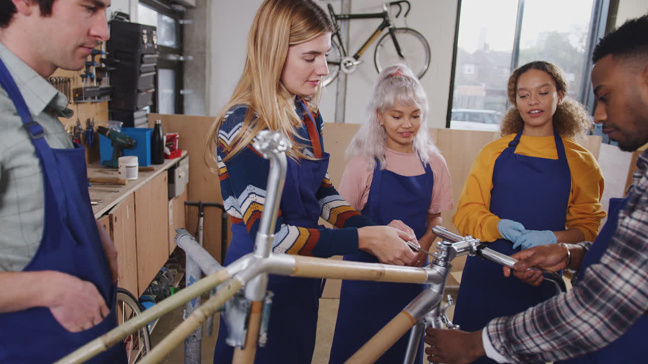 equipo multicultural de aprendices en el taller aprenden a ensamblar un marco de bicicleta construido a mano juntos