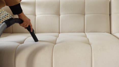 woman cleaning a couch with a vacuum cleaner