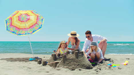 family building a sandcastle on the beach