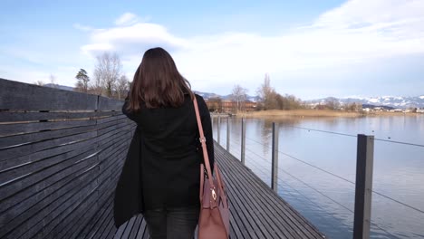 following shot of a young asian woman walking and looking back on a pier with a big smile in slow motion in rapperswil, switzerland