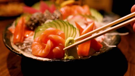 chopsticks picking sashimi with wasabi garnish