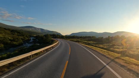 conduciendo un coche en una carretera de noruega al amanecer.