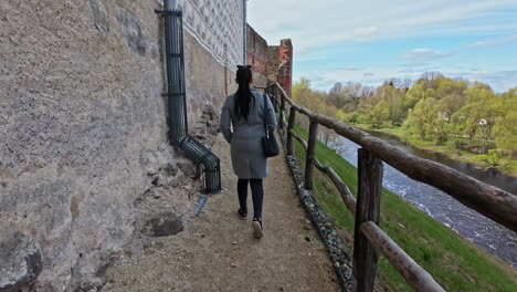 Frau,-Lange-Schwarze-Haare-Zu-Fuß-In-Der-Mittelalterlichen-Burg-Bauska-In-Lettland-In-Der-Nähe-Des-Flusses