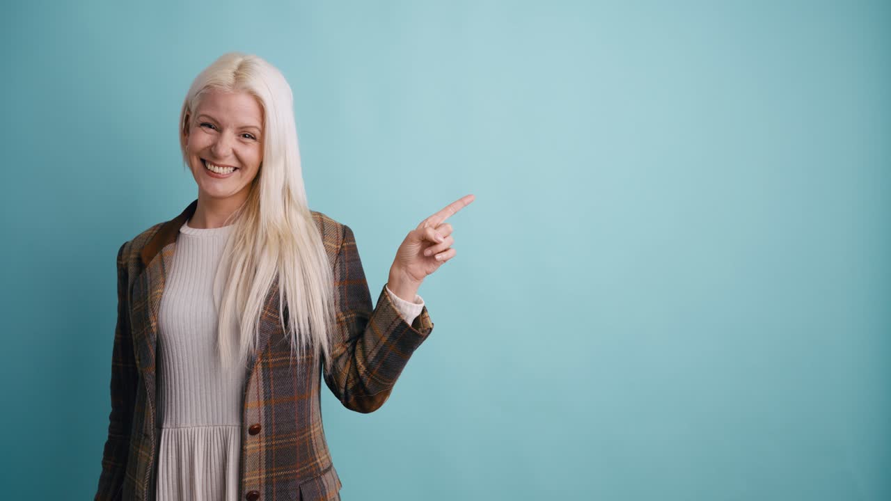 Happy Blonde Woman Smiling and Pointing to Copy Space