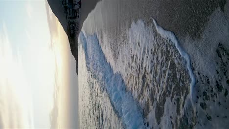 Vertikale-Aufnahme-Eines-Wunderschönen-Strandes-Mit-Wellen,-Die-Sich-Nach-Sonnenuntergang-In-Albanien-In-Zeitlupe-Bewegen