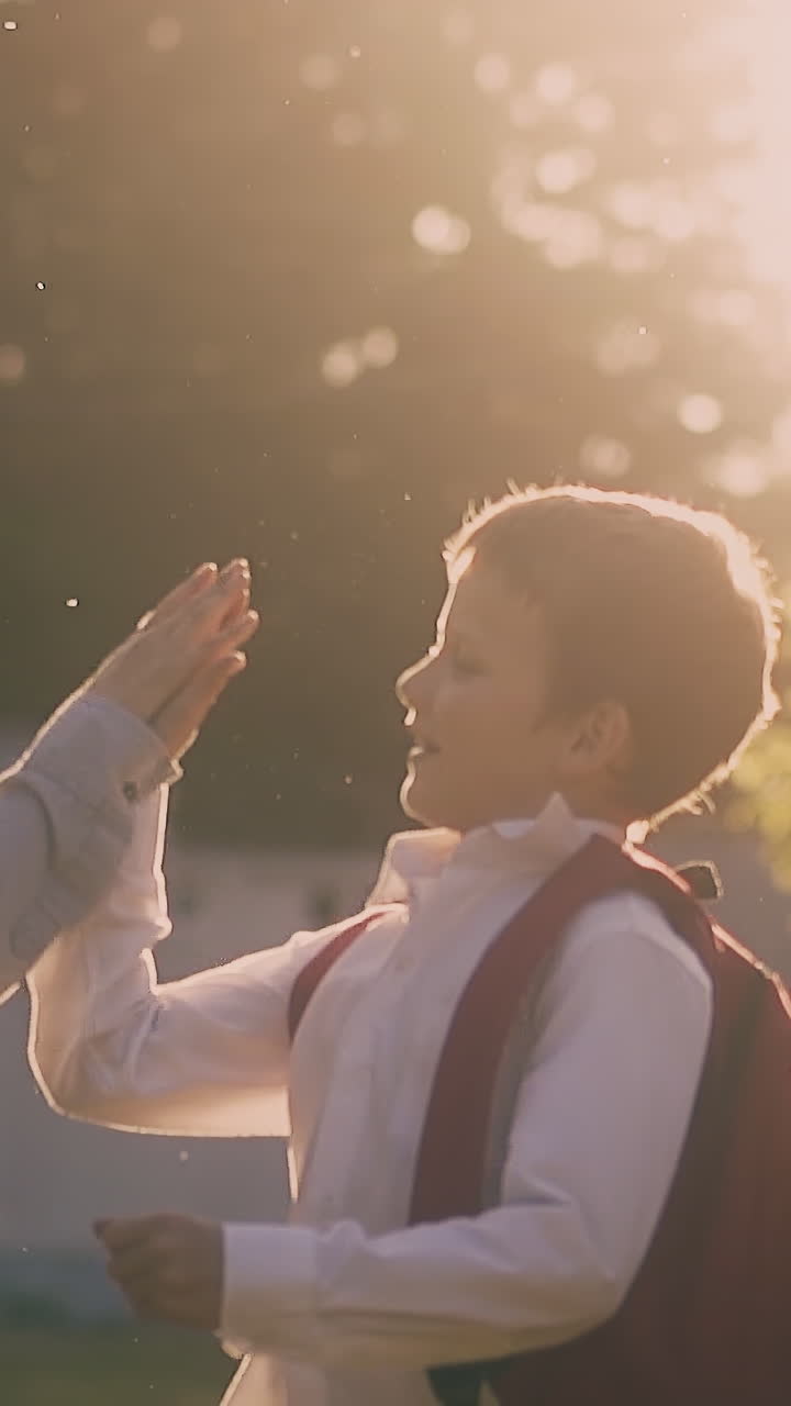 happy schoolboys throw pile of papers and give five at school year end walking in park at back sunlight slow motion