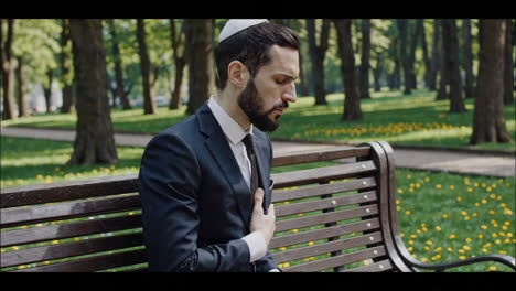 man in suit praying in park