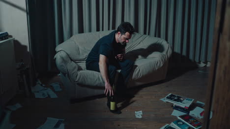 man sitting alone on a sofa, drinking alcohol