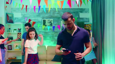 Bearded-young-woman-holding-a-beer-bottle-while-browsing-on-smartphone