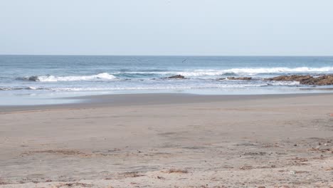 popoyo beach nicaragua with guascate rocky ocean formations hit by waves, handheld wide shot