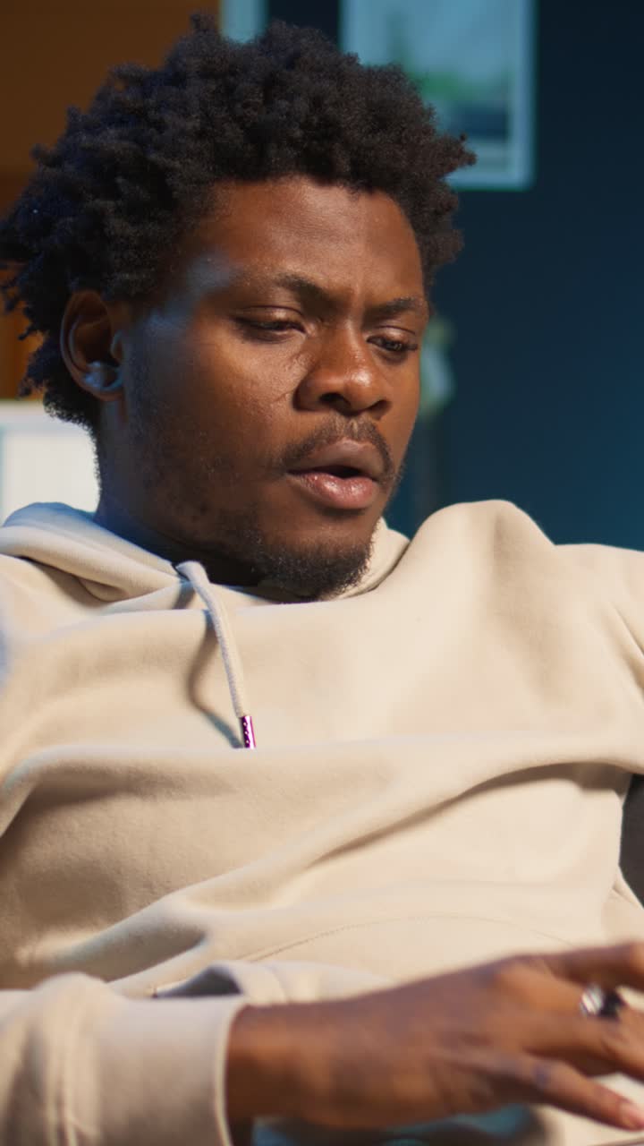 Afroamerikansk mann som jobber på laptop og drikker kaffe hjemme