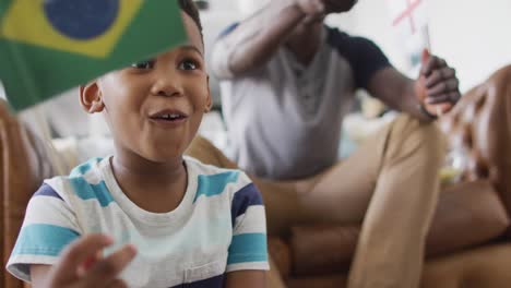 video de un niño afroamericano feliz viendo el partido con su padre