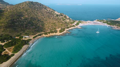 Sardinia-clear-blue-turquoise-and-calm-water-at-a-natural-sand-beach-coast-bay-in-Italy-with-sun-and-sailing-boat