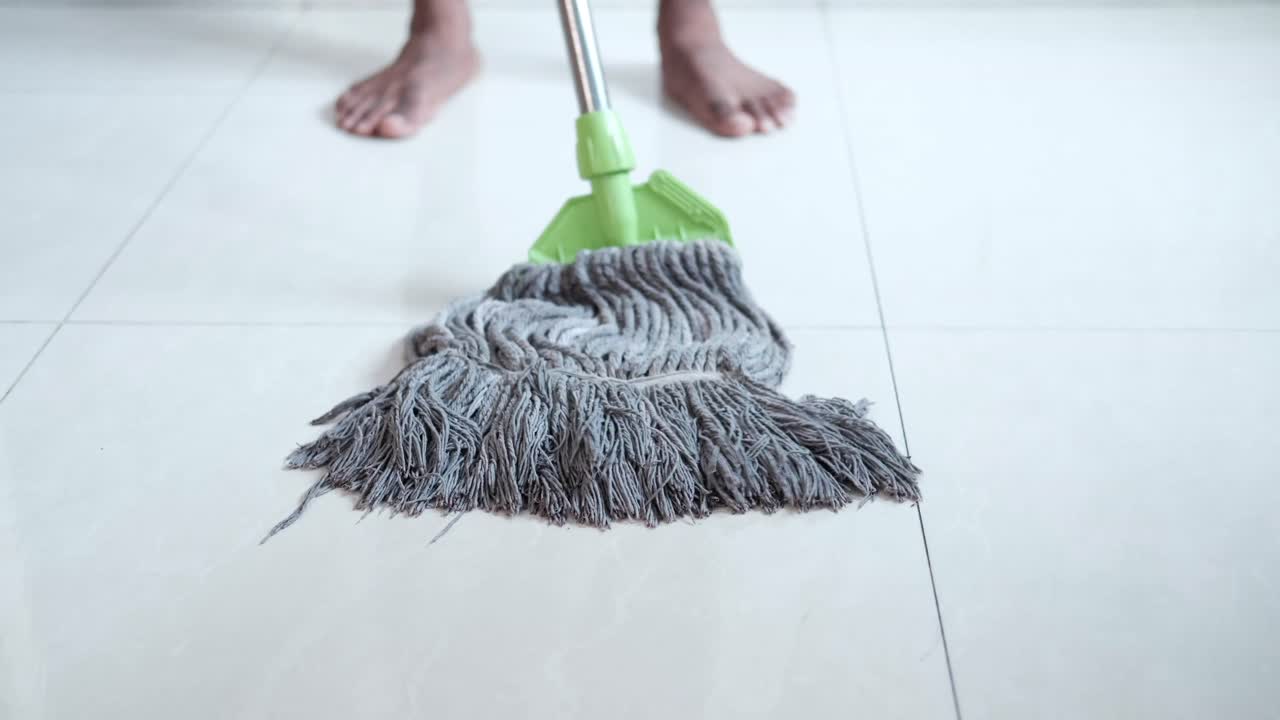 persona limpiando un piso de azulejos