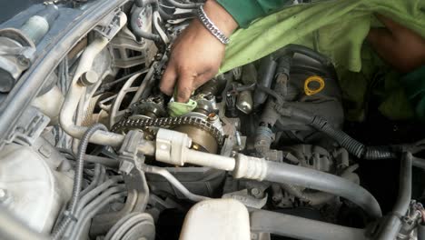 view from the top of a mechanic wiping and removing some dirt from the engine parts of a vehicle