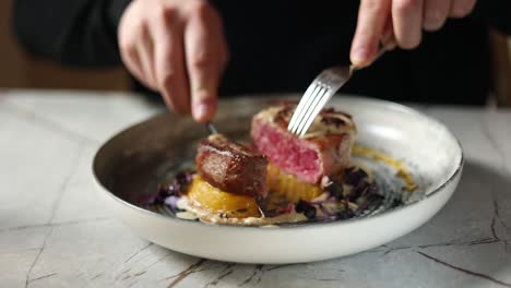 person cutting a piece of steak