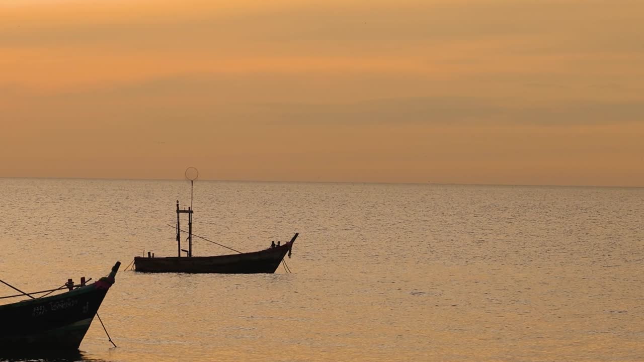배들은 조용한 해가 지는 물에서 부드럽게 떠다닙니다.