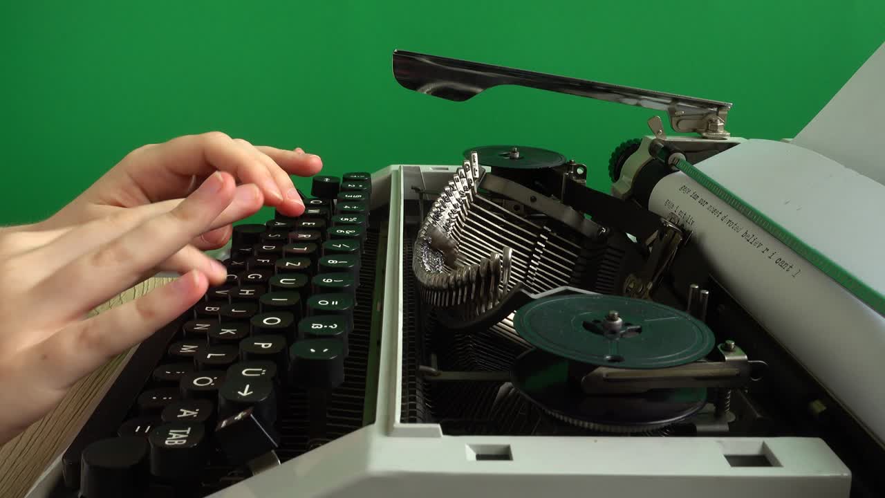 소녀는 녹색 배경에 레트로 타자기에서 타이핑하고 있습니다. chromakey.