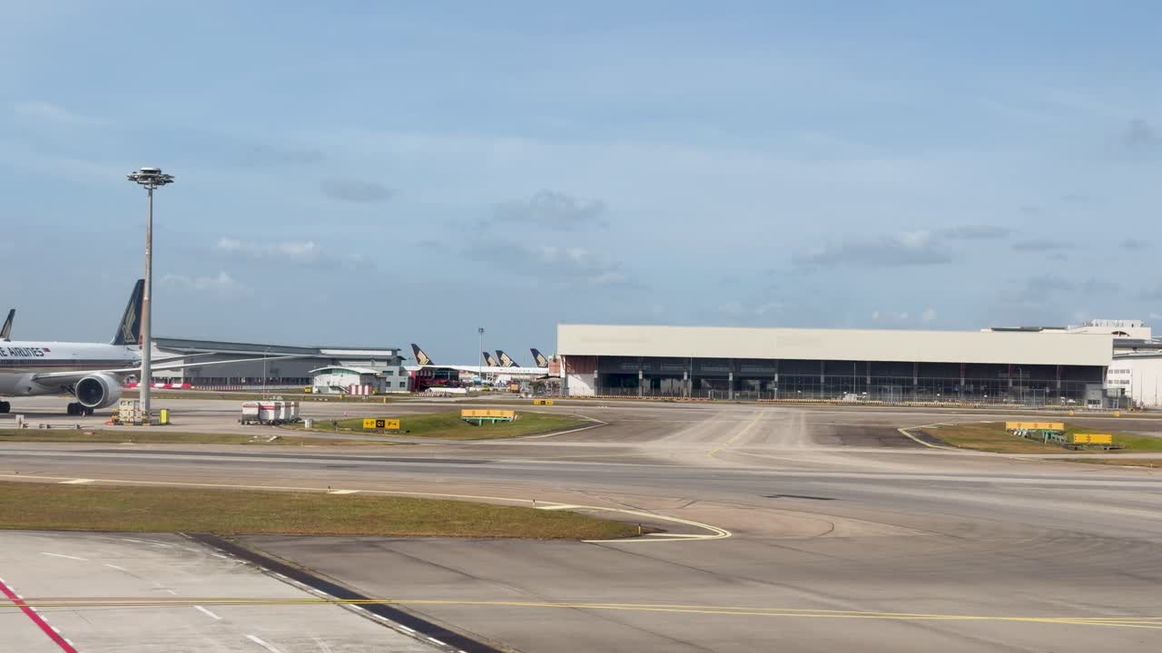 Et widebody passagerfly taxier langsomt hen over en solrig lufthavnsplads mod terminalen.