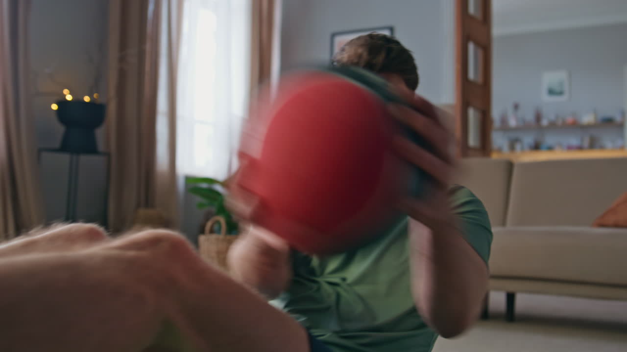 Handsome athlete training abs with ball at home closeup. Man making exercises