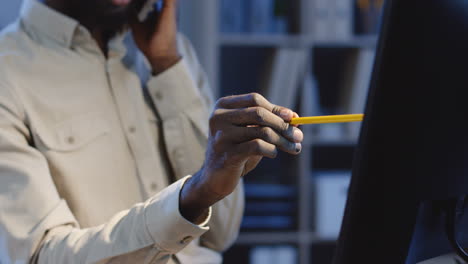 close up view of office worker speaking on the phone about work project and explaining something on the computer screen with a pencil in a hand