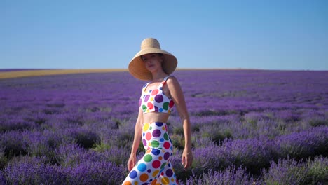 woman in a multicolored suit with circles and a hat holds large inflatable