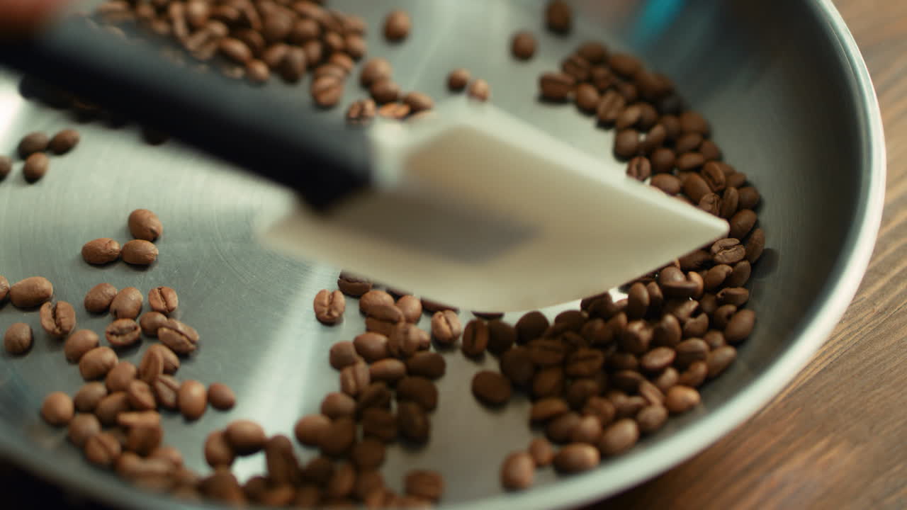 Mixing coffee beans on pan by scapula during roasting. Ingredient for drink