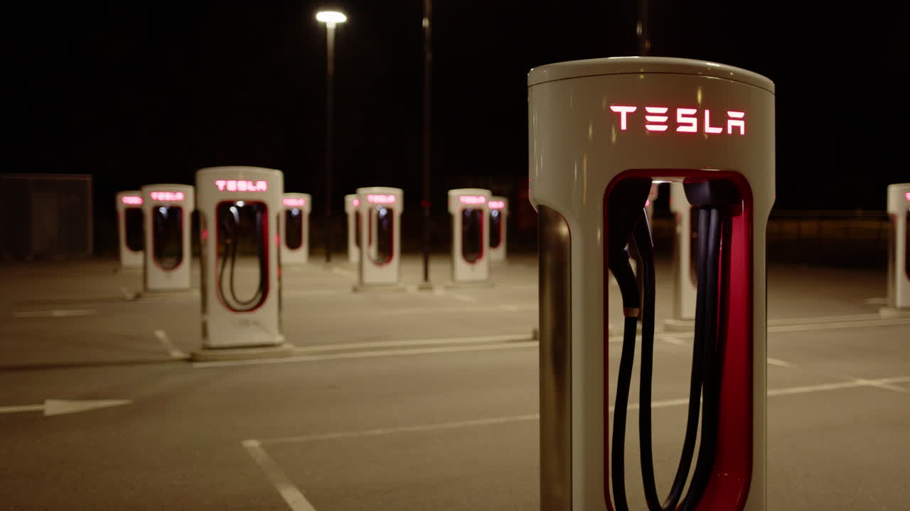 Pan shot of deserted Tesla Supercharger charging stations at night