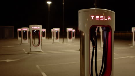 pan shot of deserted tesla supercharger charging stations at night