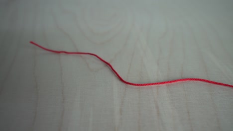 bola de hilo rojo en una mesa de madera