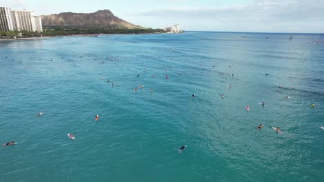 a drone circles around surfers paddling out to catch waves at a tropical beach location